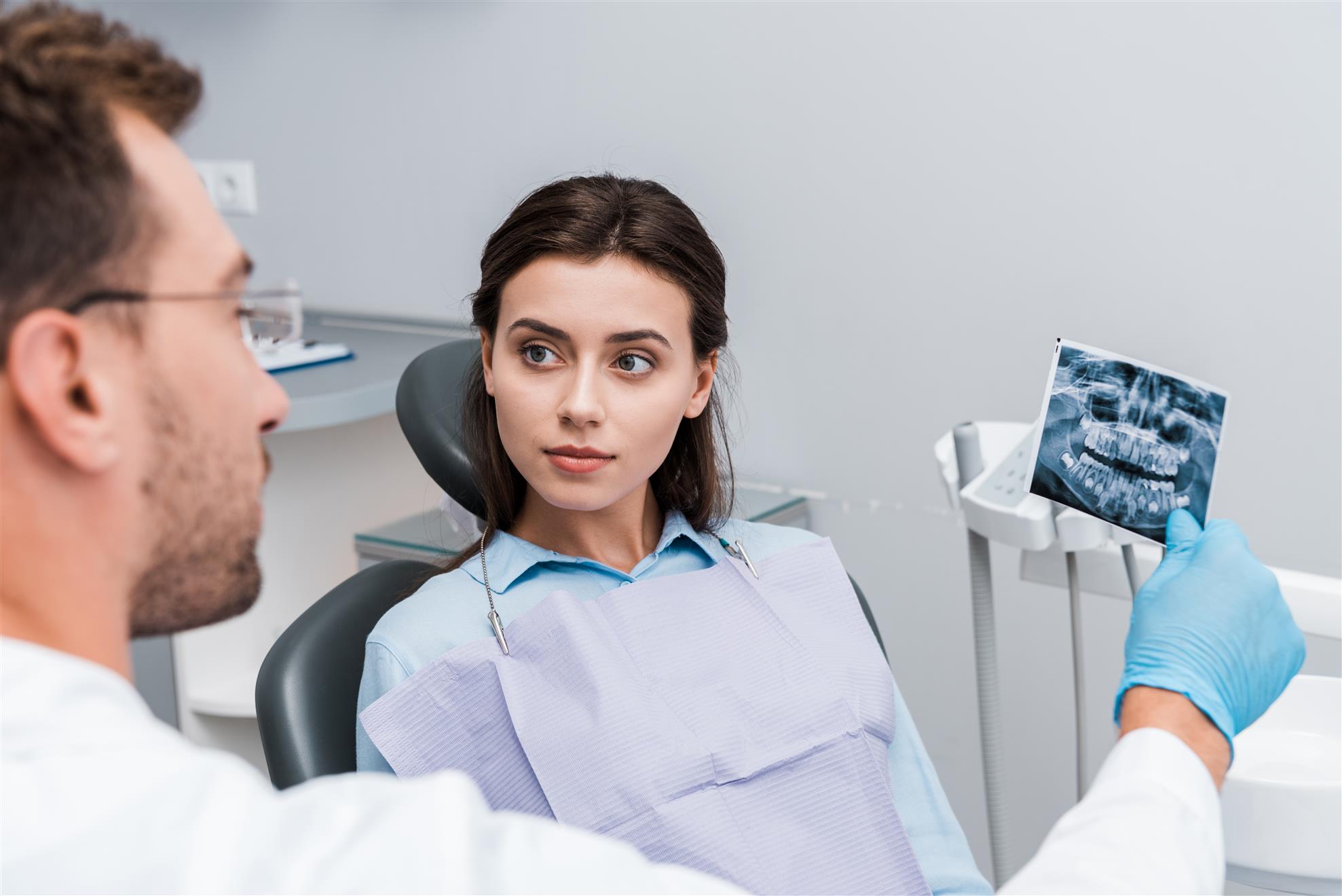 רופא שיניים ומטופלת מסתכלים על צילום שיניים
